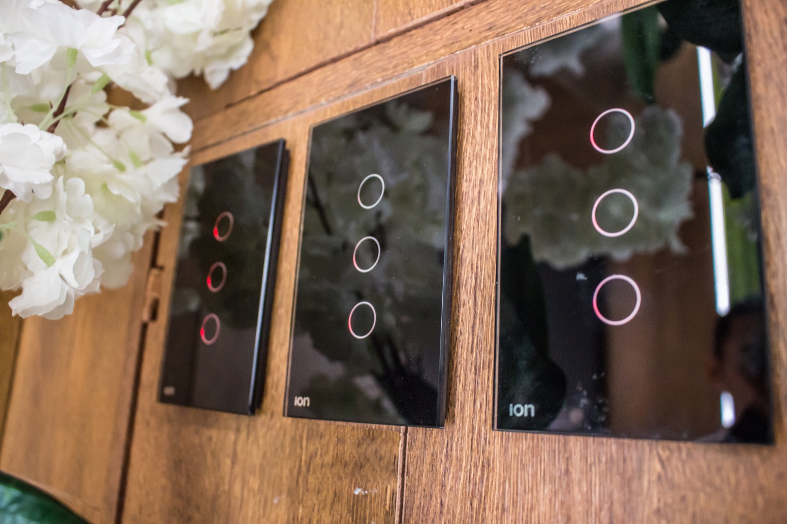 Interruptores ION Glass negros instalados en panel de madera oscura — línea premium con touch LED